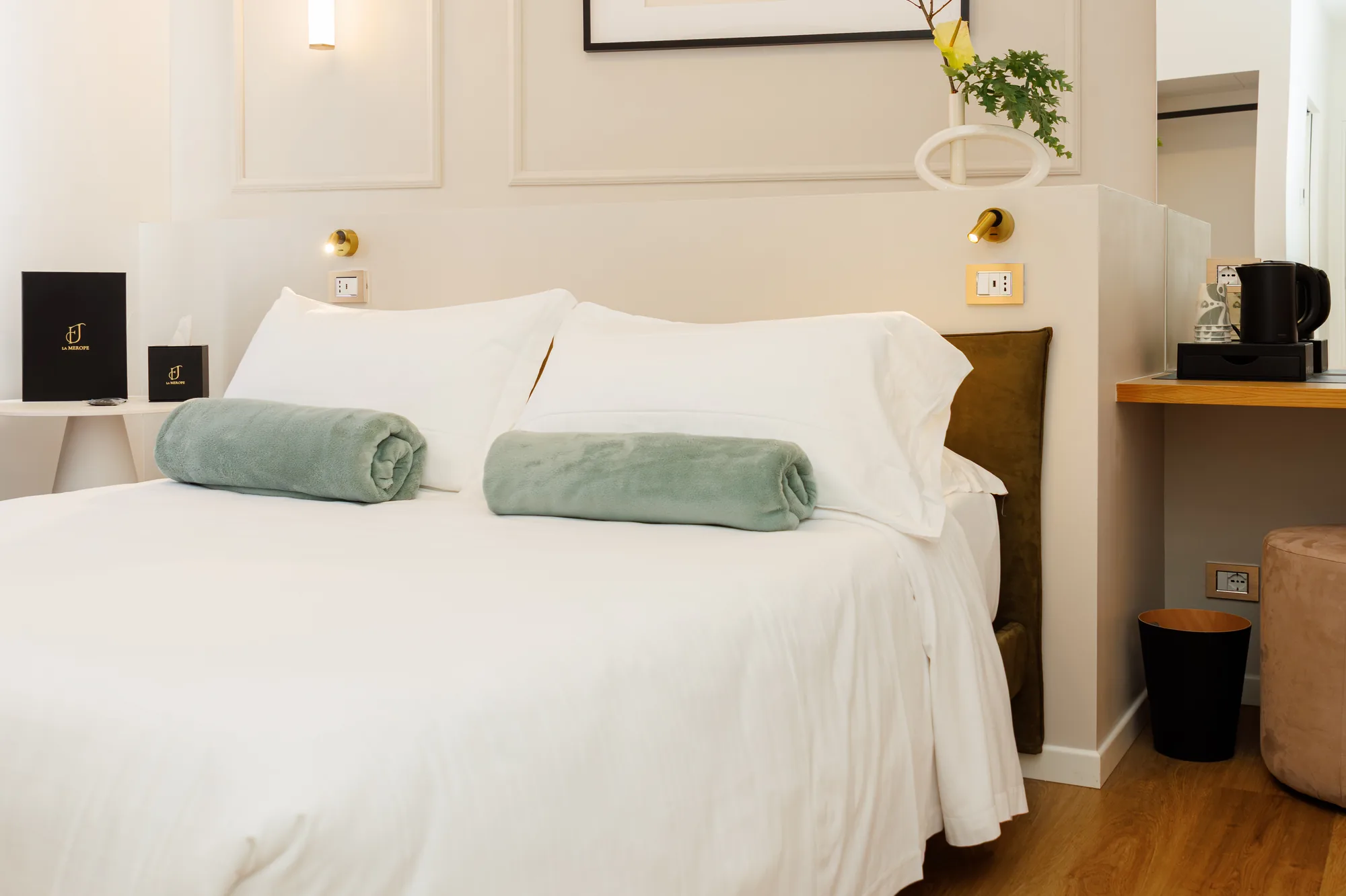 Camera da letto con letto matrimoniale, coperte verdi, comodino e angolo caffè