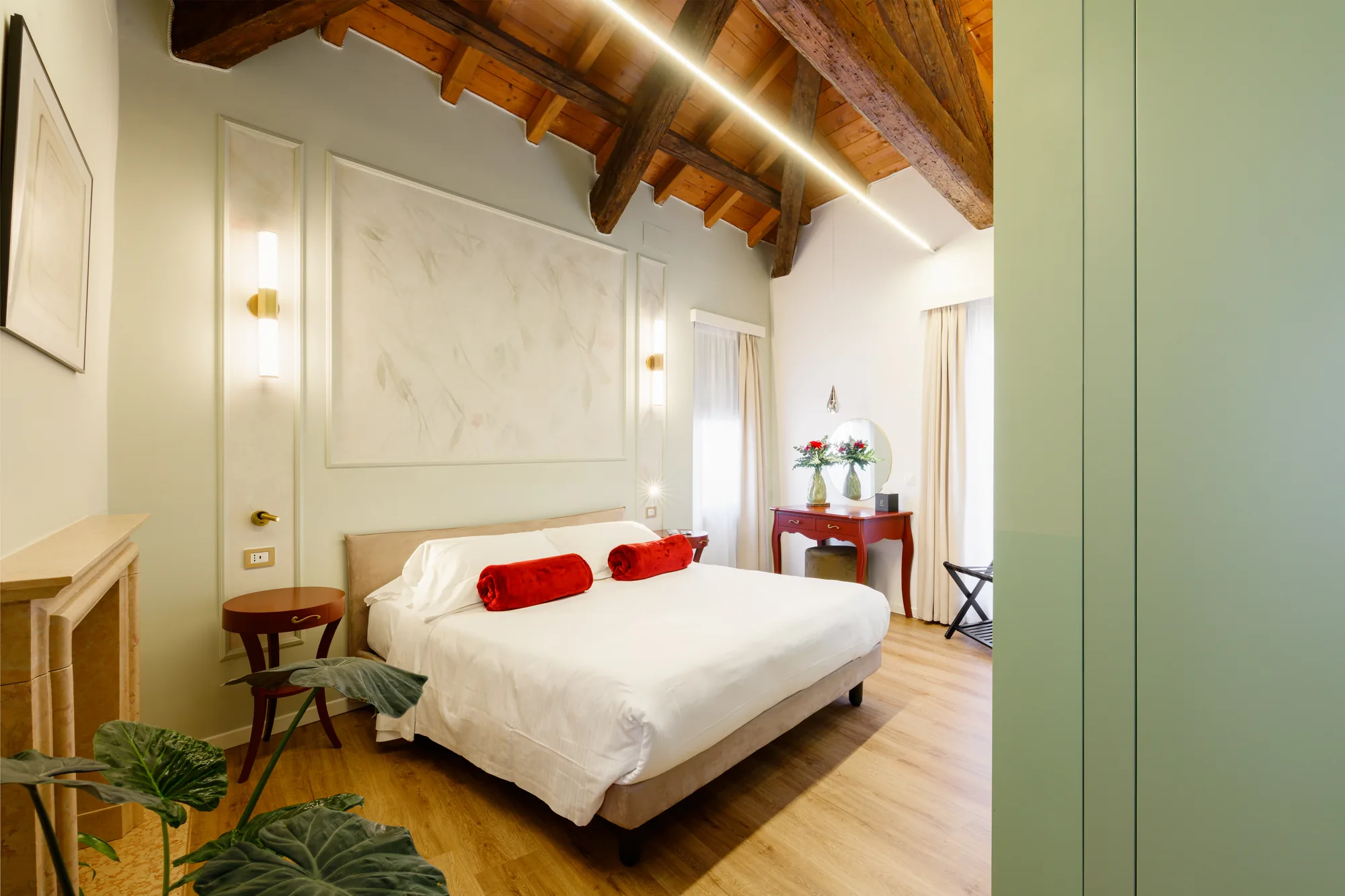 Camera da letto elegante con letto matrimoniale, decorato con asciugamani rossi, mobili moderni e soffitto in legno a vista