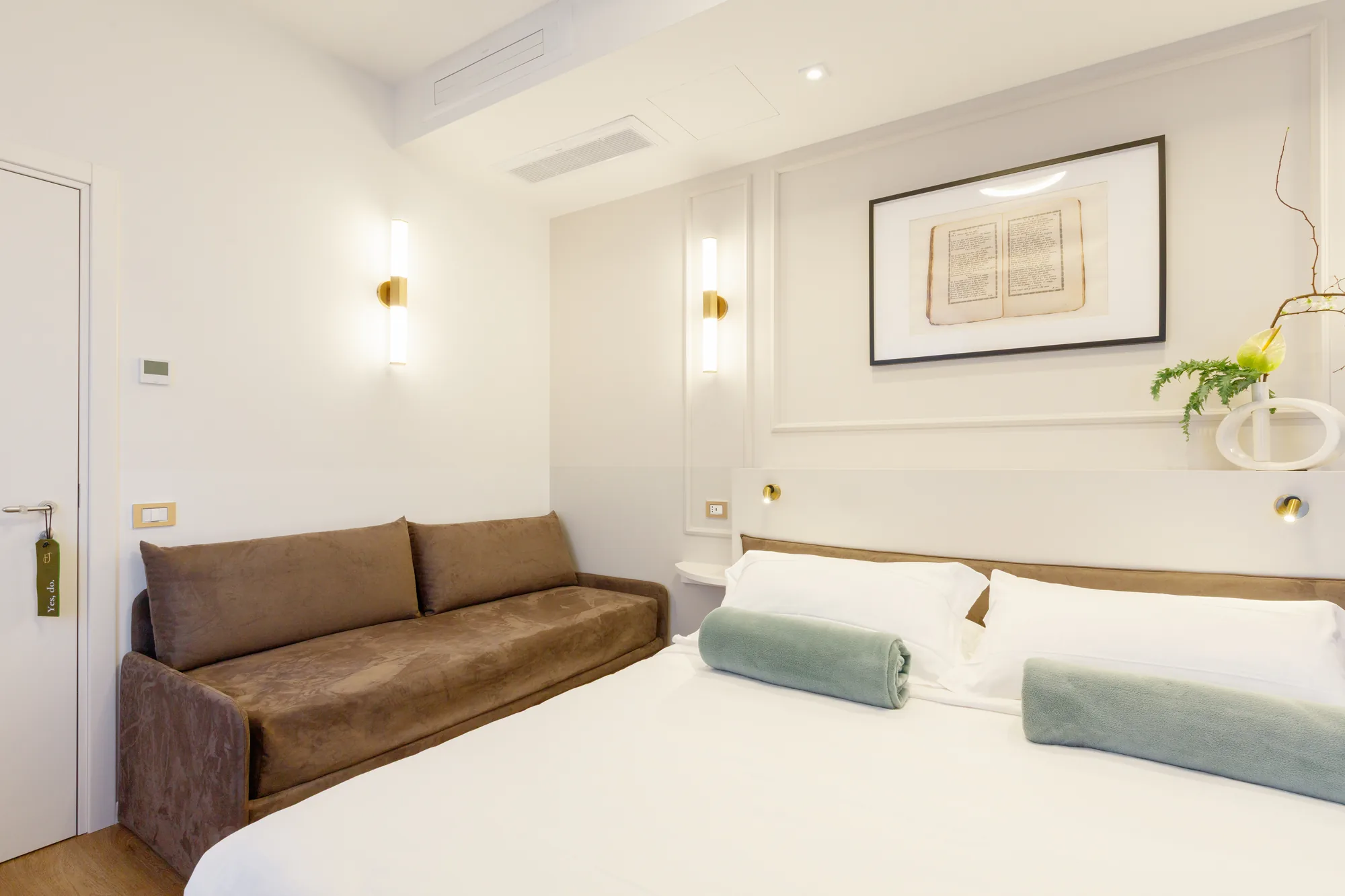 Camera da letto moderna con un divano marrone, letto matrimoniale e decorazioni minimaliste