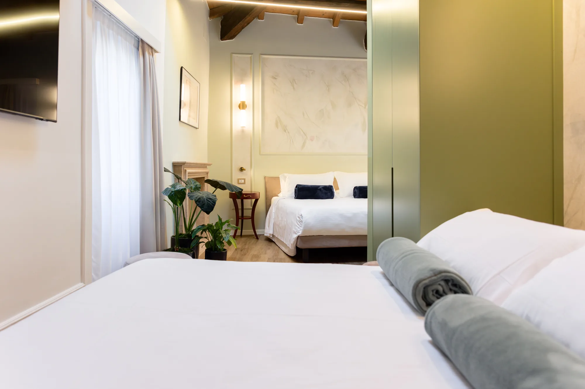 Camera che mostra una camera da letto con un letto matrimoniale, piante e un armadio verde