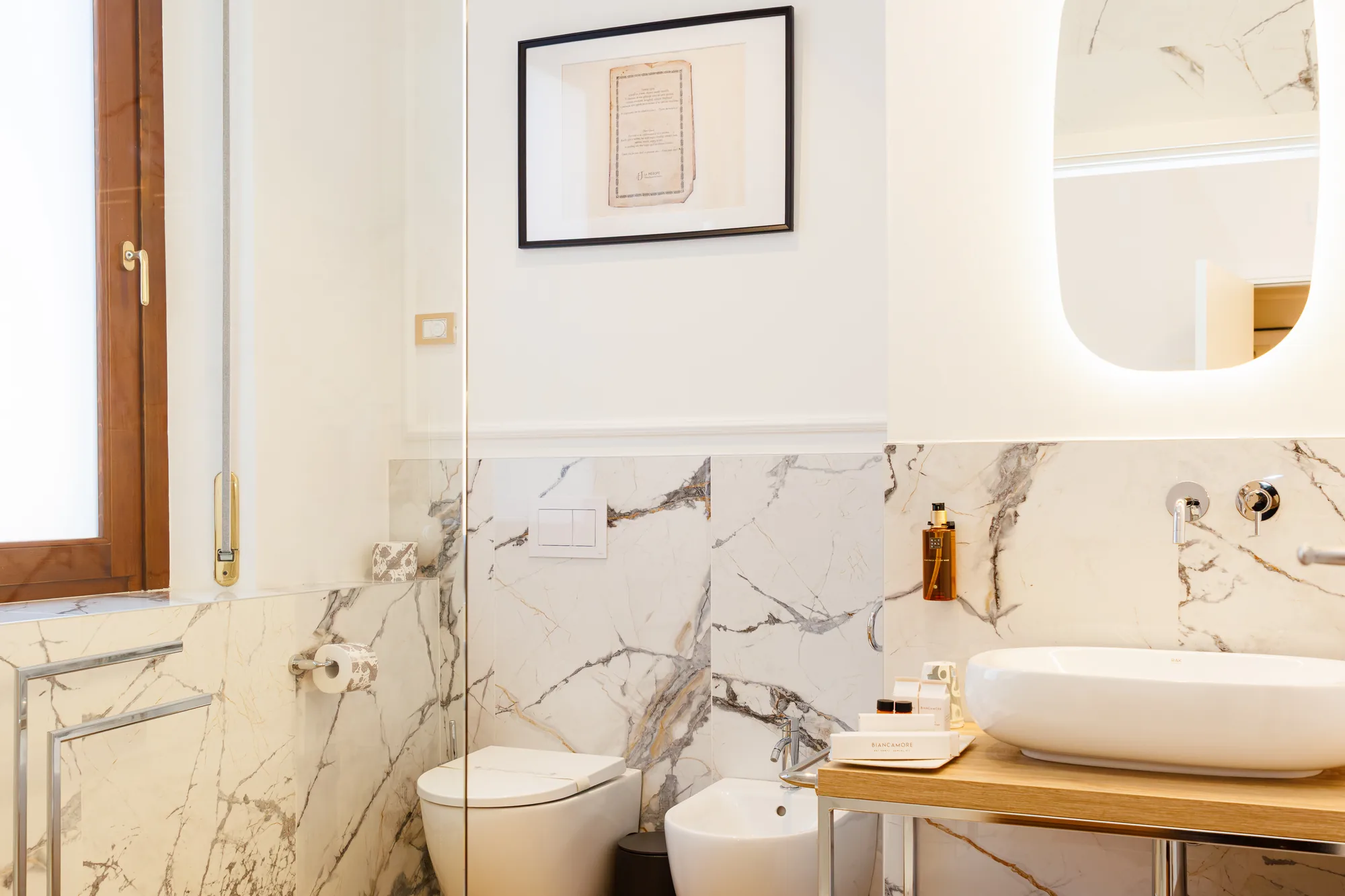 Interior of an elegant bathroom with marble walls, modern sink, and a hanging painting