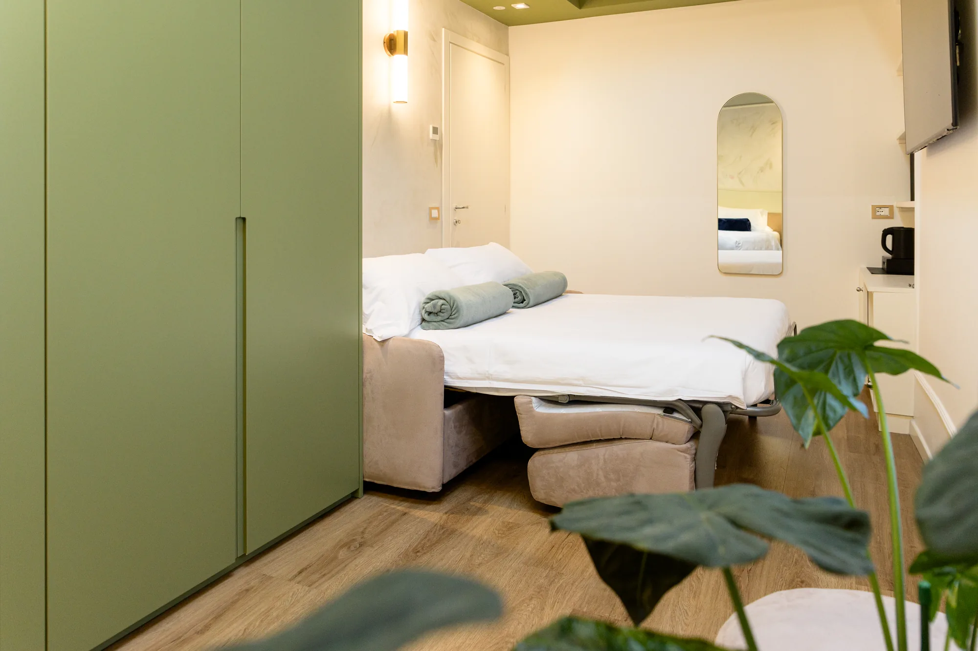 Camera da letto moderna con un letto matrimoniale, armadio verde e piante decorative